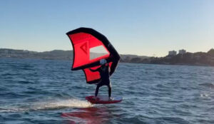a person on a surfboard with a red sail